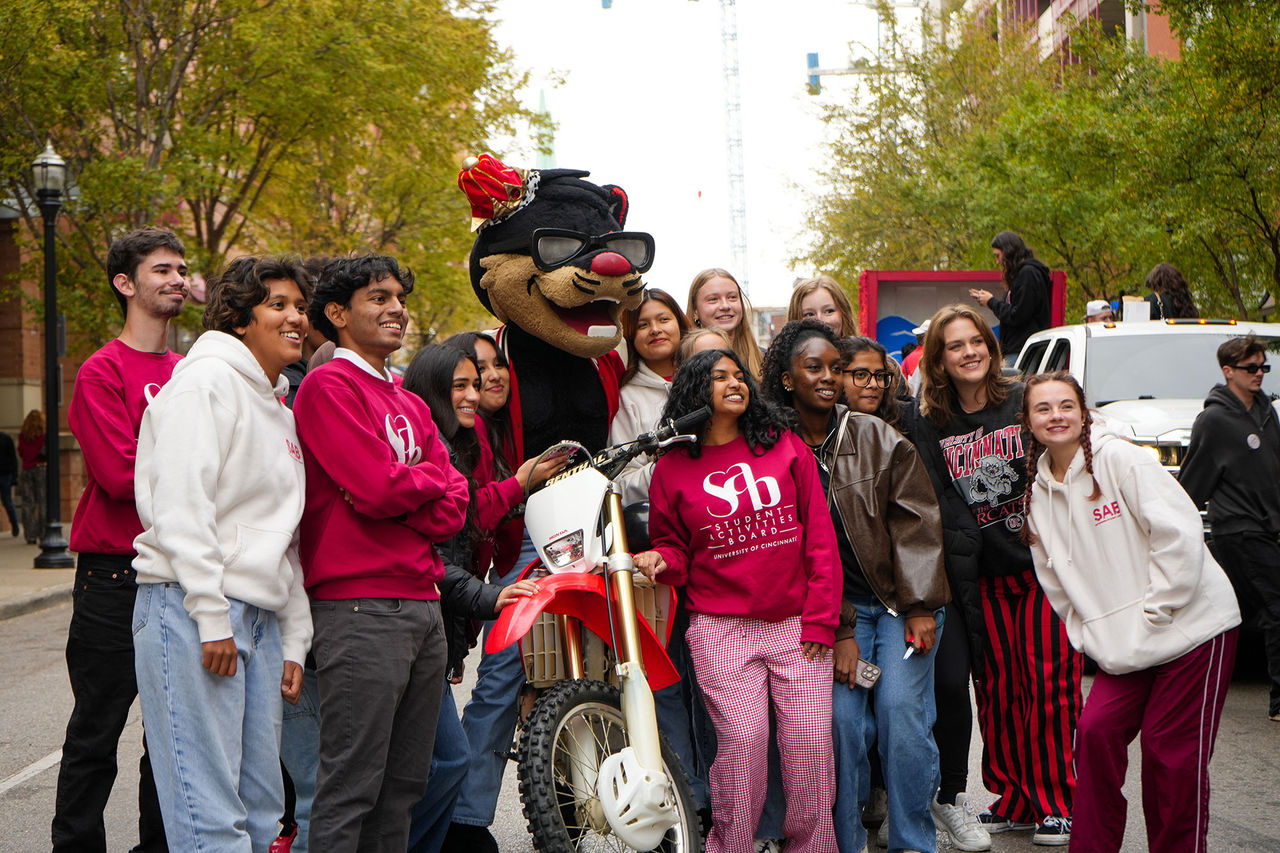 A group of CECH students gather around the Bearcat mascot before the UC Homecoming Parade
