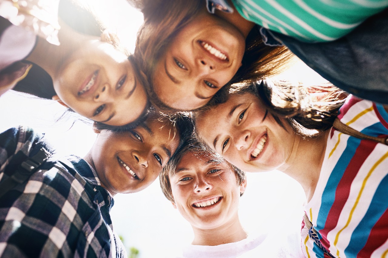 Low angle portrait of a group of diverse schoolchildren standing in a huddle.