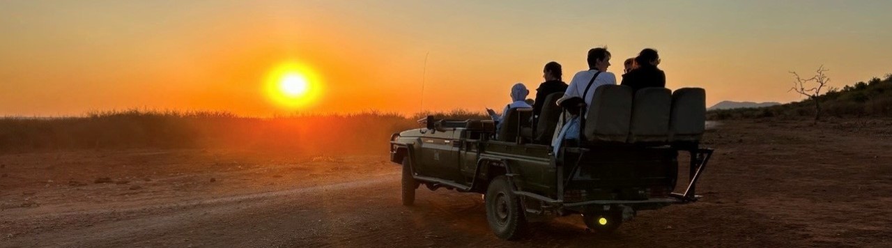 Students posing in front of the sunset in Africa